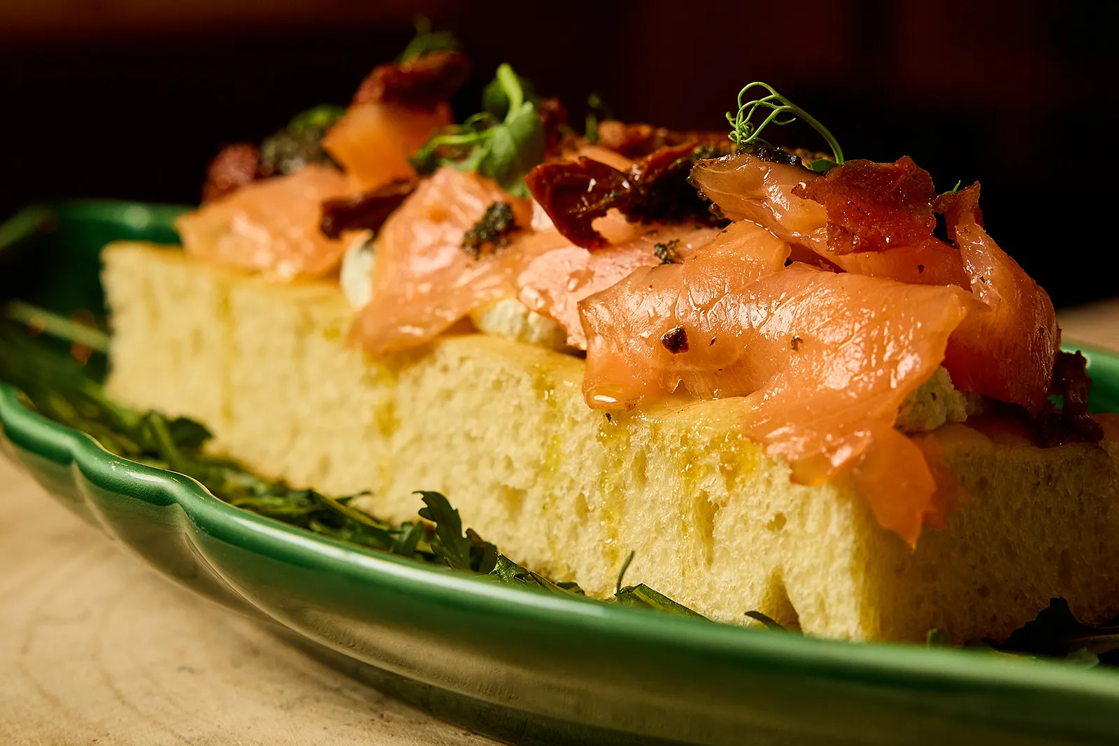 Pinsa au saumon avec Ricotta, pesto, tomates séchées et roquette servie au restaurant italien In Casa à Levallois-Perret